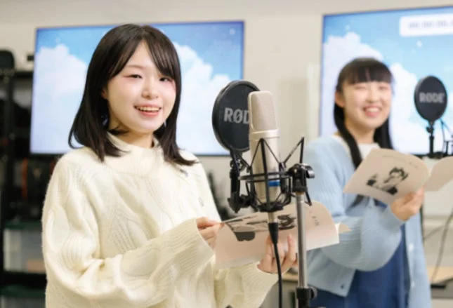 レコーディングスタジオで笑顔でマイクに向かう2人の若い女性
